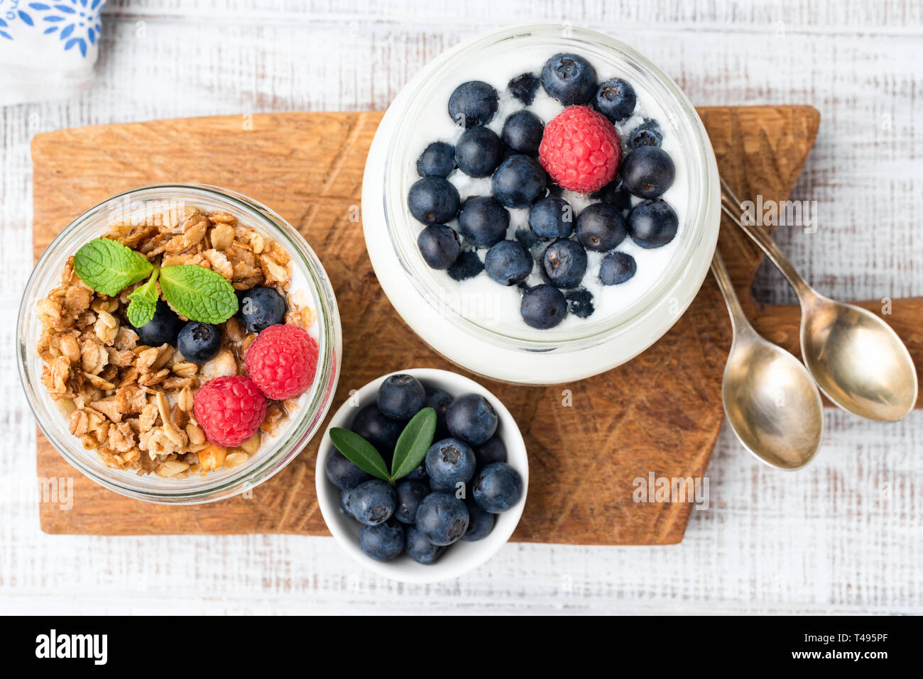 Yogurt, granola and blueberries in jar on wooden board, table top view. Healthy eating, healthy lifestyle, dieting or weight loss concept Stock Photo