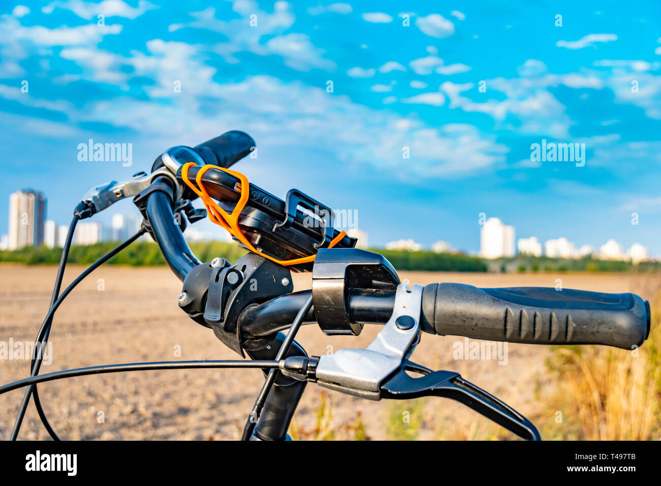 View over the handlebar of a bicycle. In the background you can see a field and the unfocussed satellite town of Gropiusstadt in Berlin-Neukölln. Stock Photo