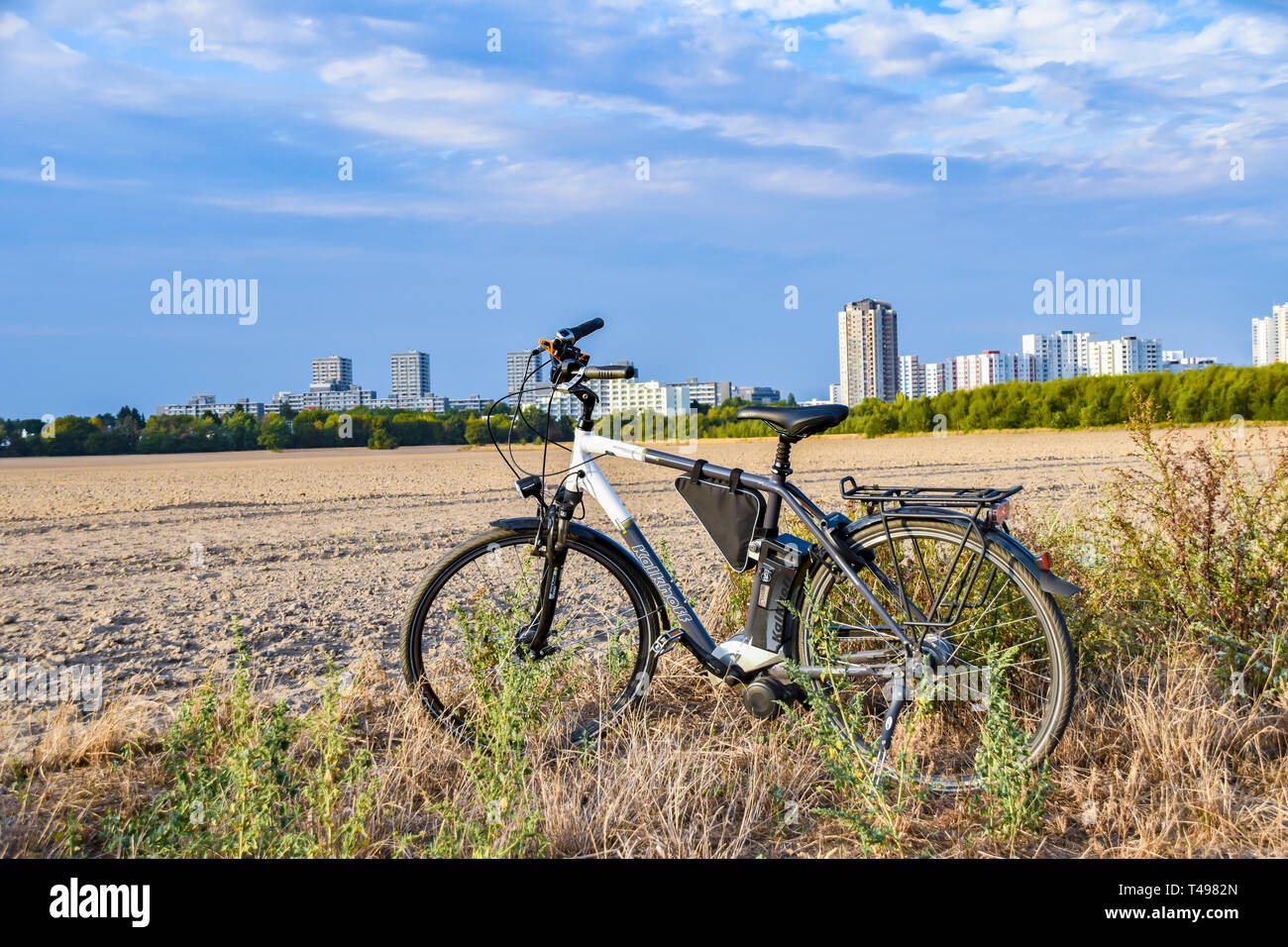 Berlin, Germany - September 12, 2018: Bicycle standing near a field. In the background you can see the satellite town Gropiusstadt in Berlin-Neukölln. Stock Photo