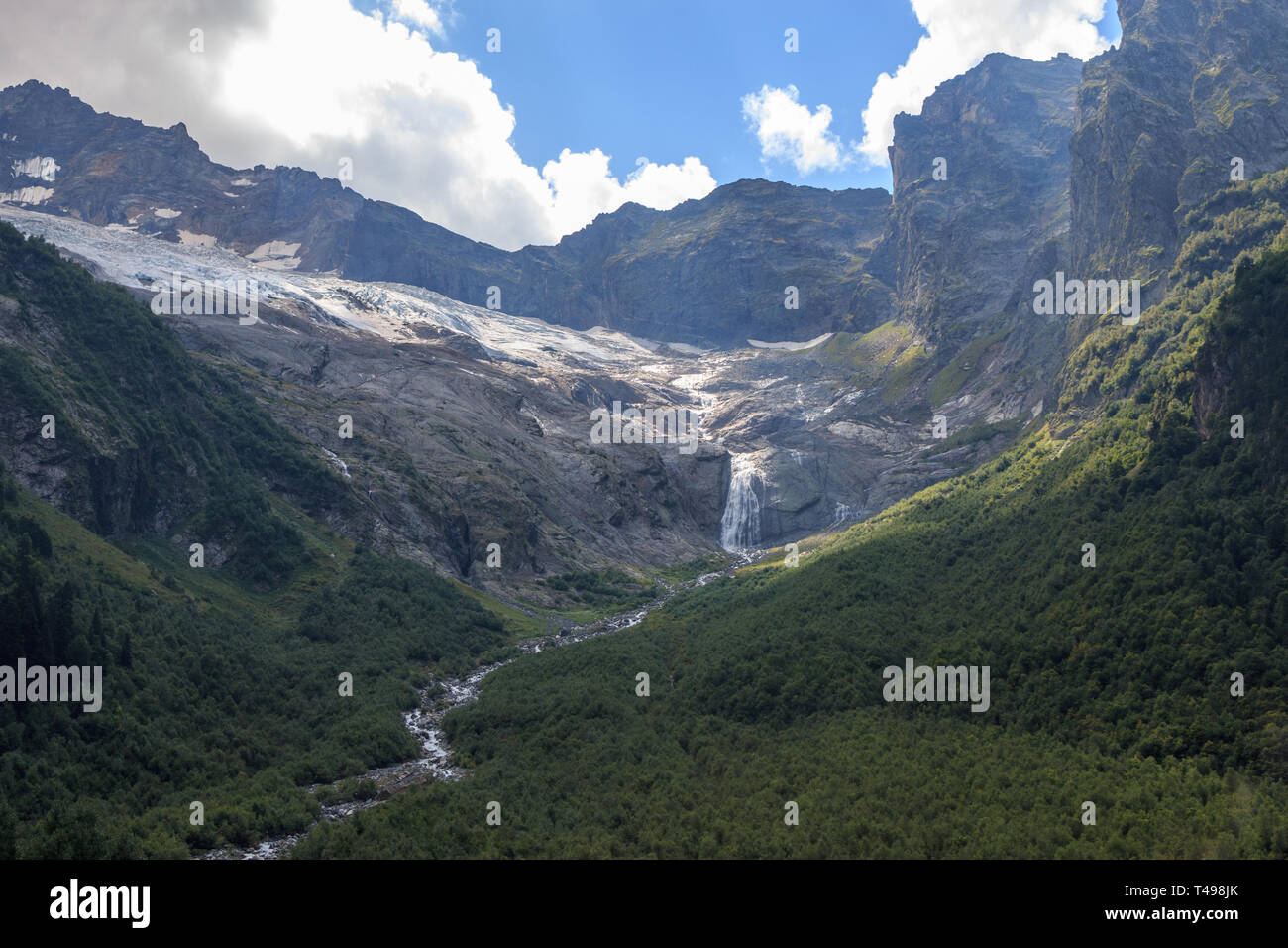 Closeup view mountains scenes and far away waterfall in national park Dombai, Caucasus, Russia, Europe. Summer landscape, sunshine weather and sunny d Stock Photo