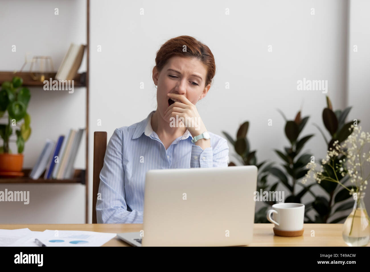 Sleepy bored businesswoman yawning at workplace feeling deprived in office Stock Photo