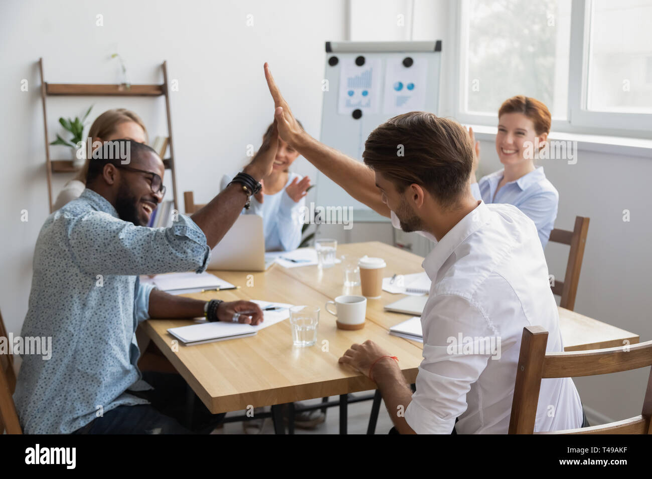 Happy diverse male colleagues giving high five celebrating shared win ...
