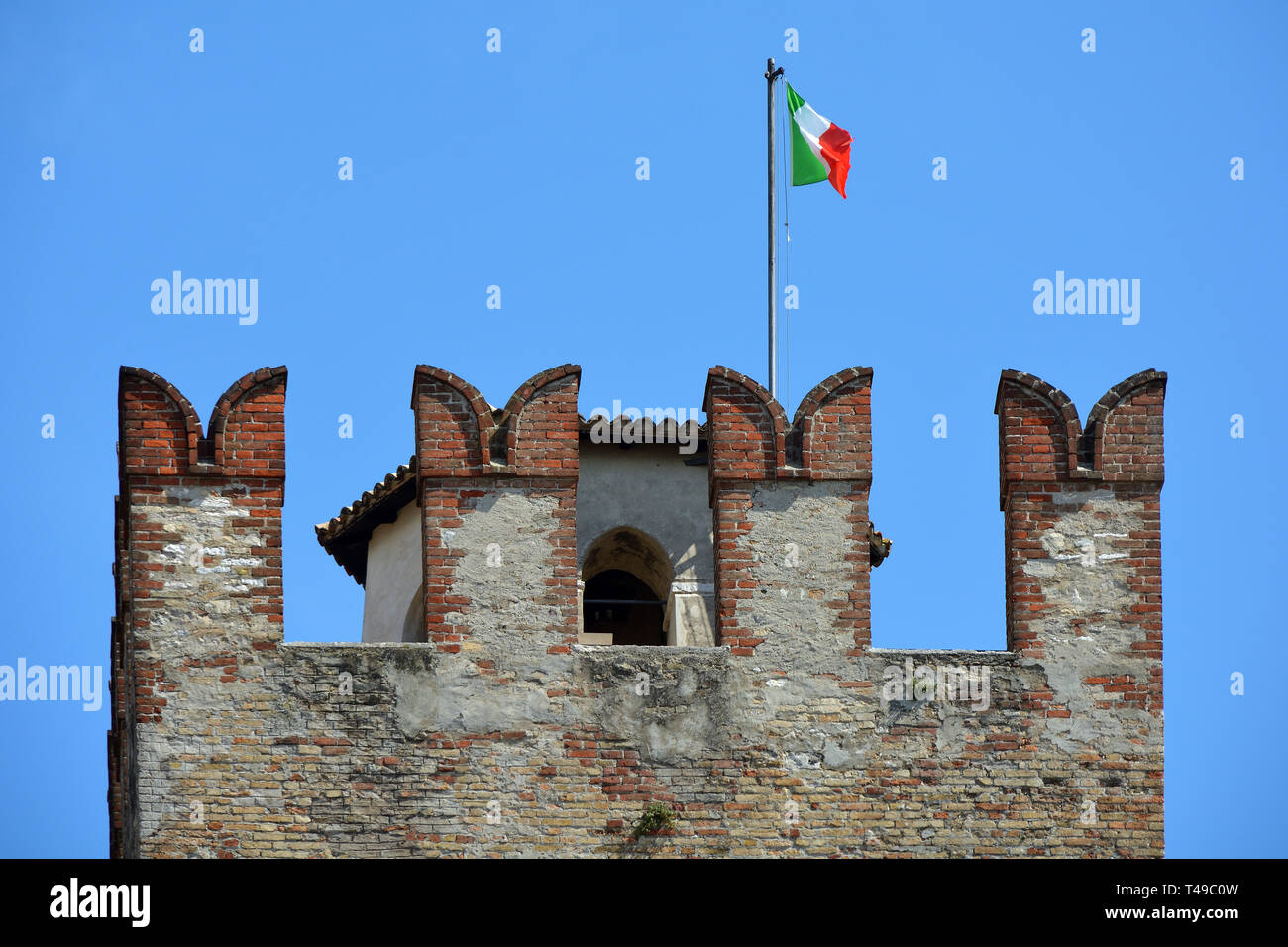 Scaligero Castle in a detail view with the Italian flag in the historic center of Sirmione at Lake Garda - Italy. Stock Photo