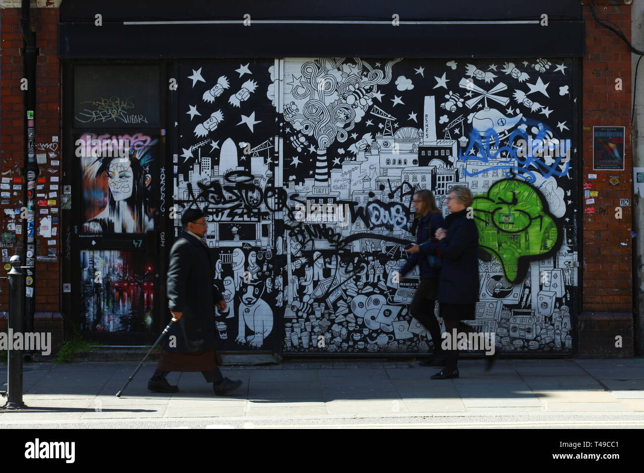 People multiracial walking in front of a street art wall, Brick lane, Spitalfields, London, United Kingdom Stock Photo