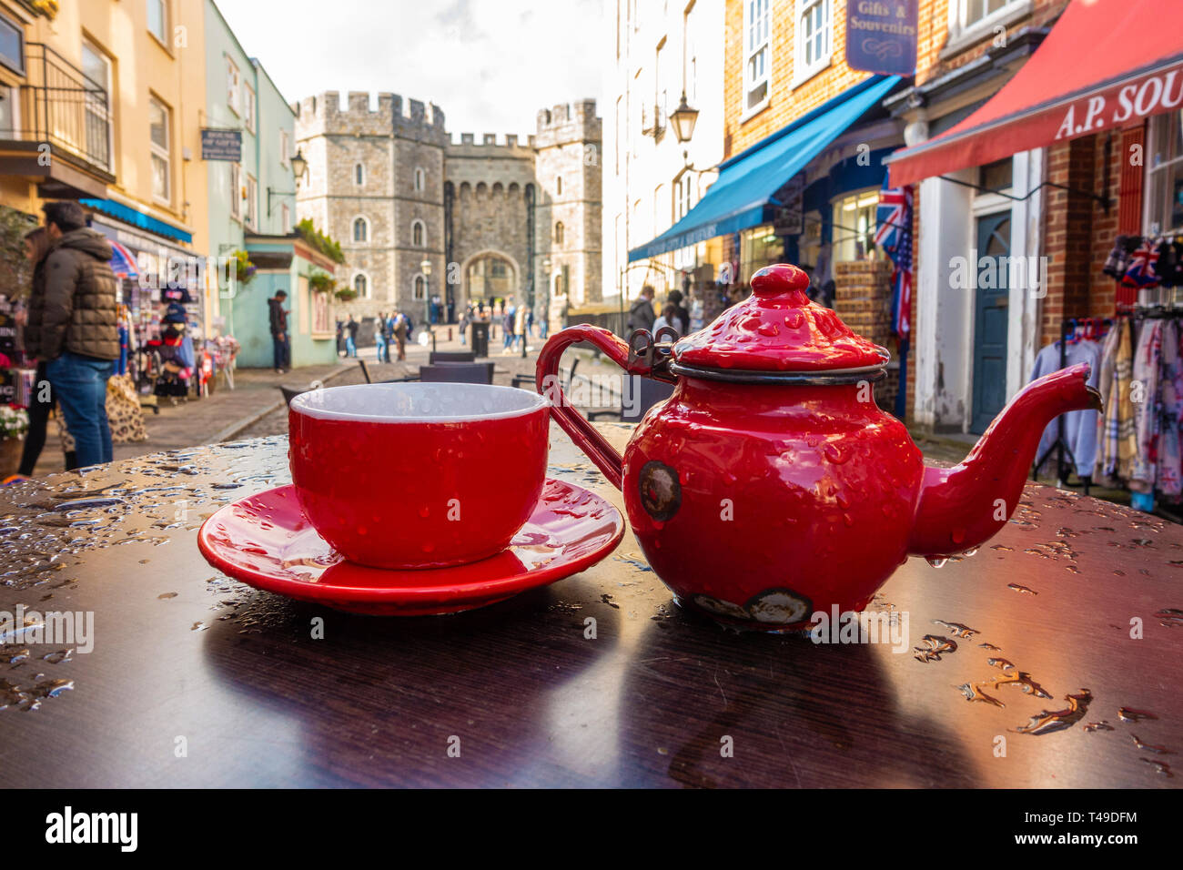 A bright red teacup, saucer and teapot form an eye catching centrepiece on an outdoor cafe table in Church Street, Windsor, UK Stock Photo