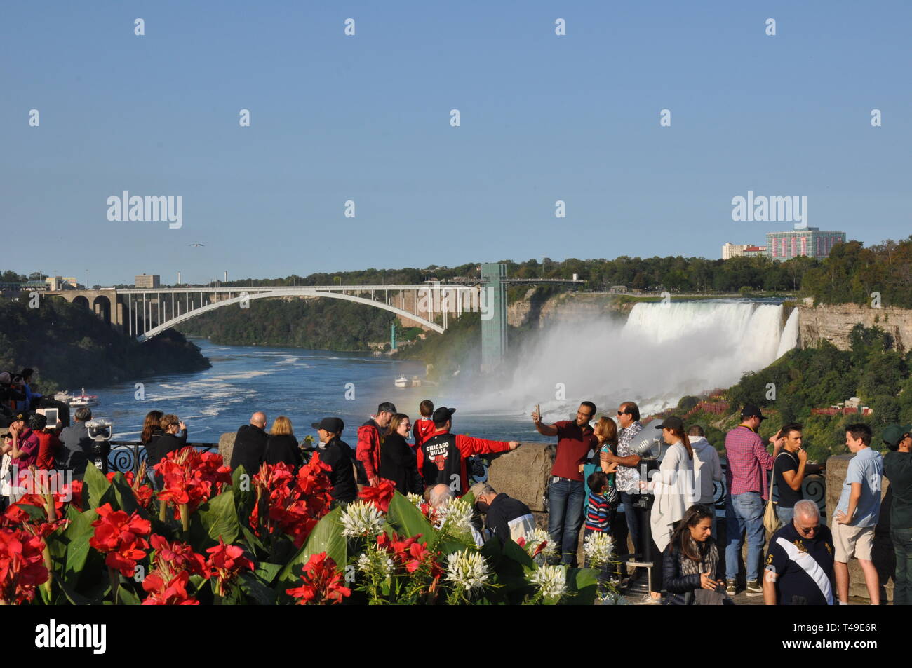 Niagara Falls, Canada - September 10, 2018 - Rainbow of People and Canni Lilies at Table Rock Viewing Horseshoe Falls in Niagara Falls, Canada - Edito Stock Photo