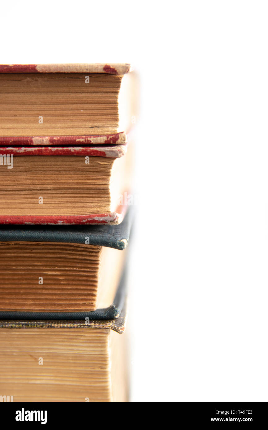 Old worn books stacked on white surface close up with copy space Stock Photo
