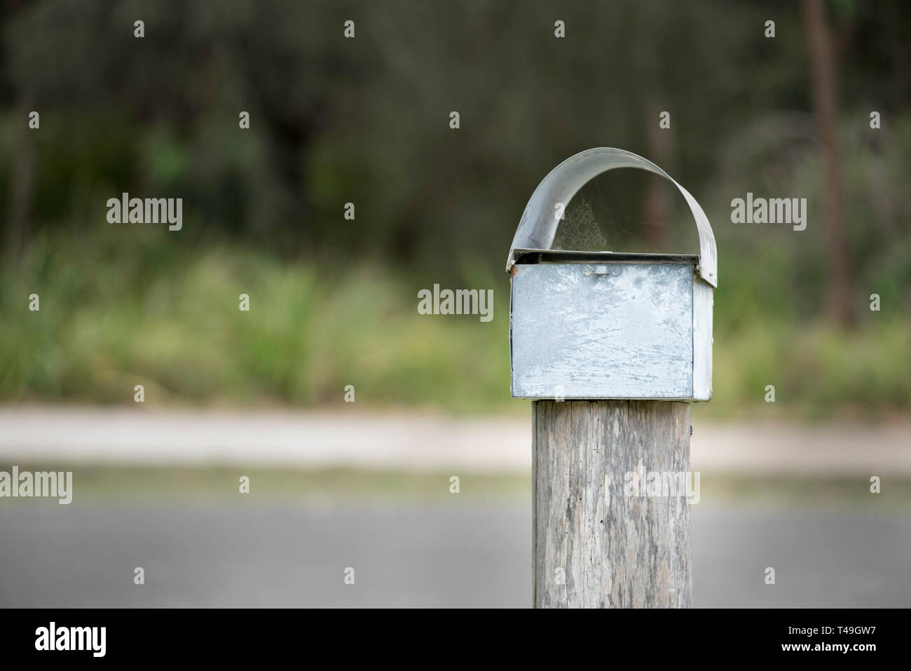 The blank rear end of a traditional metal letterbox mounted on a Eucalyptus (Gum Tree) hard wood post in a suburban rural village in Australia Stock Photo