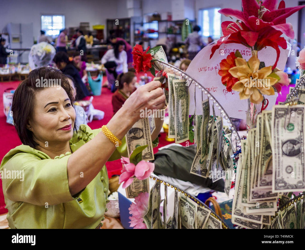 Des Moines, Iowa, USA. 14th Apr, 2019. A woman puts dollar bills on a money  tree which will be donated to the temple during Lao New Year, also called  Songkran, observances at