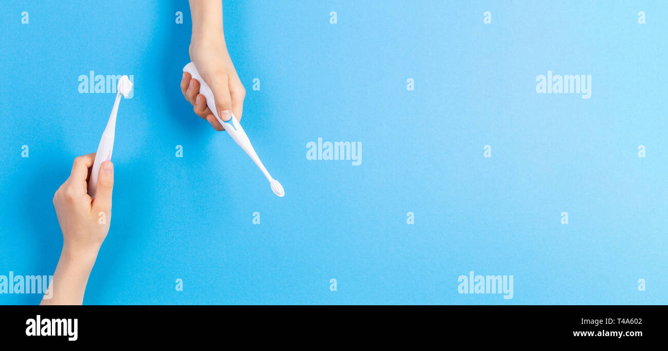 Kid hands with electric toothbrushes on blue background Stock Photo