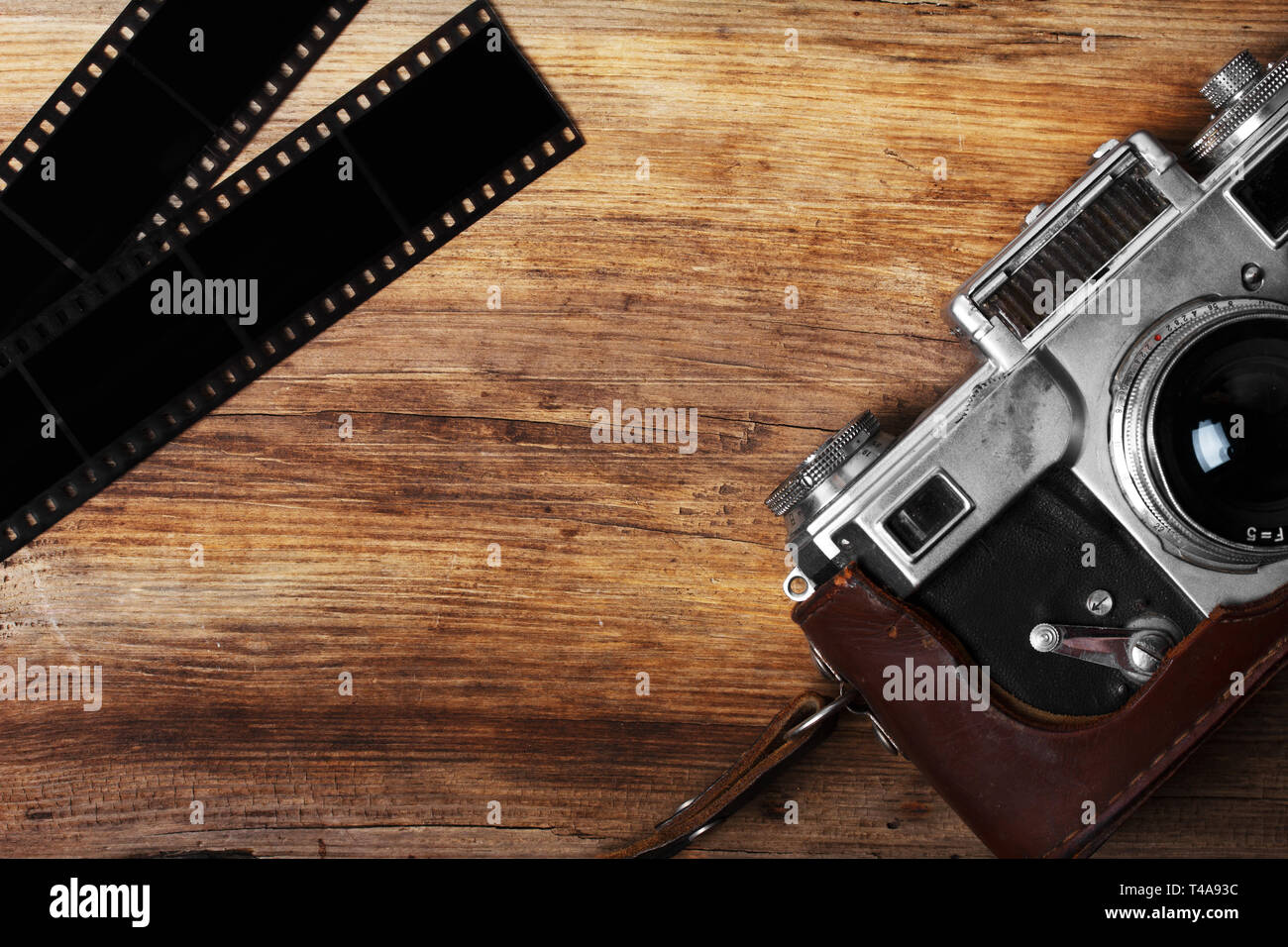 old camera and blank film strip on wooden table Stock Photo