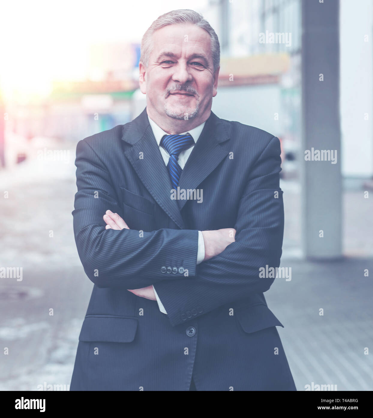 portrait of a successful businessman standing with crossed hands in ...