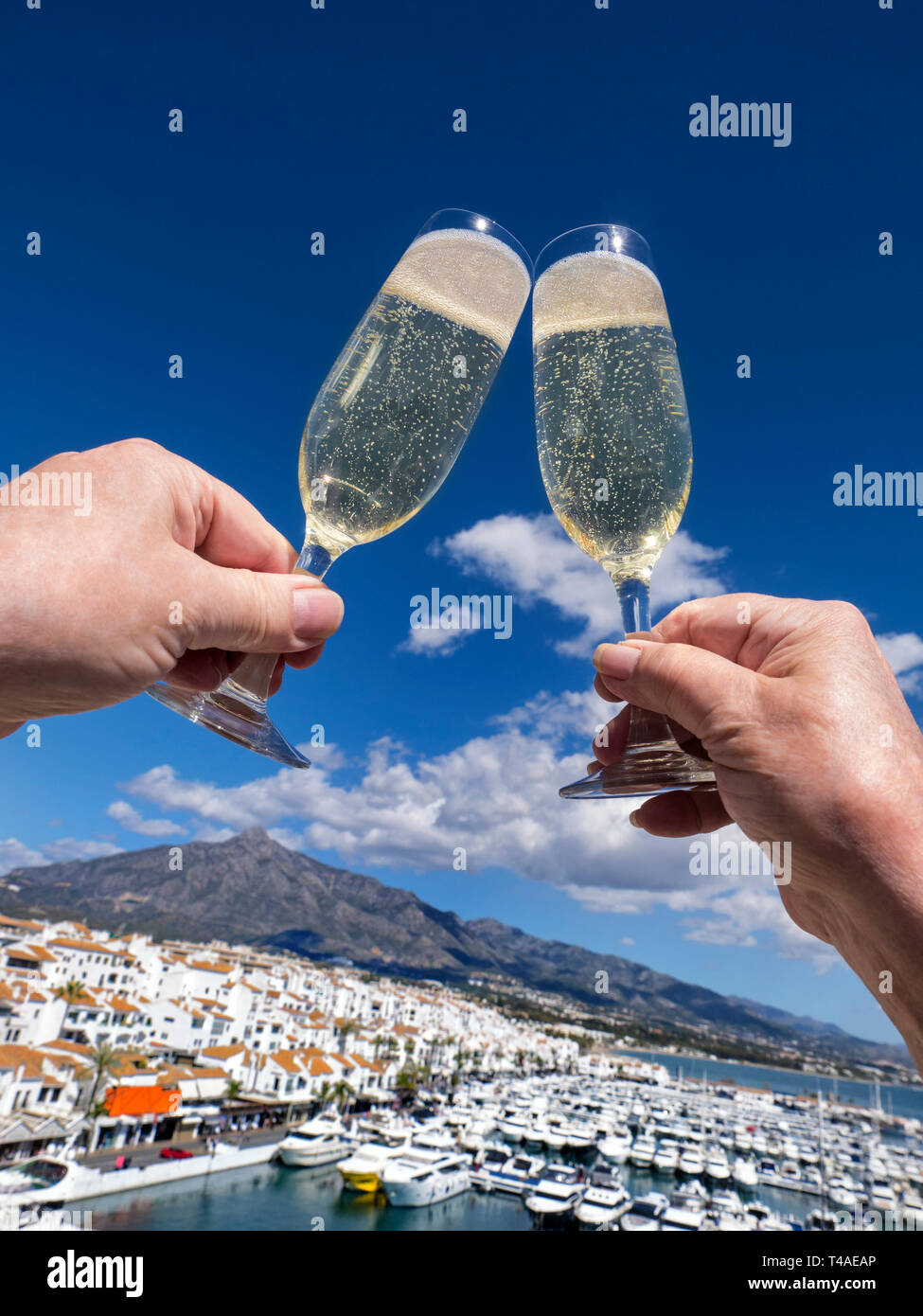 Celebrating Spain holiday champagne  lifestyle alfresco chinking cheers, vacation vista Puerto Banús marina Marbella Costa del Sol Andalusia Spain Stock Photo