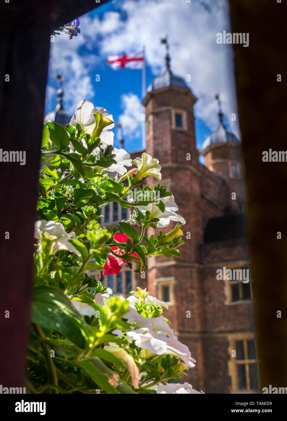 GUILDFORD HISTORIC FLORAL spring flowers viewed through old railings with Cross of St George flag on Jacobean Abbot's Hospital Guildford Surrey UK Stock Photo