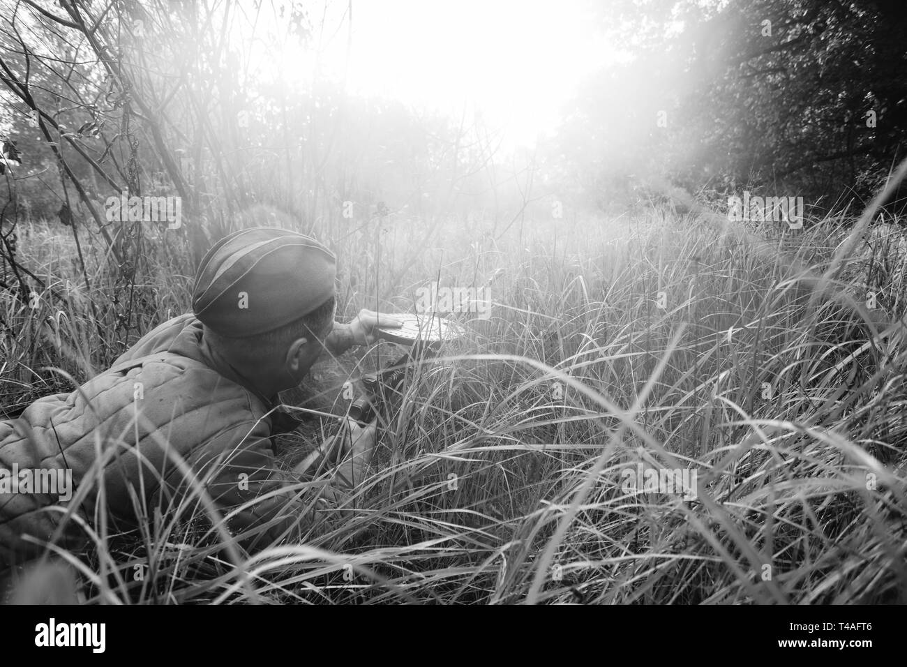 Re-enactor Dressed As World War II Russian Soviet Red Army Soldier Reload Machine Gun in Forest Grass During Battle. Degtyaryov DP Machine Gun. WWII W Stock Photo