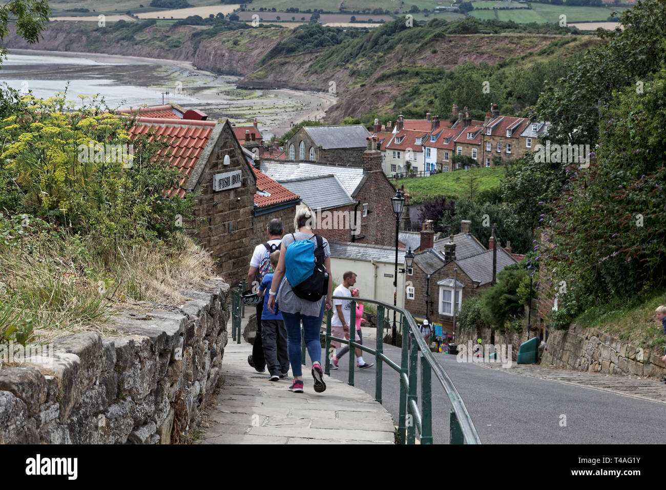 Tourists walking down the steep hill of Robin Hood's Bay , North