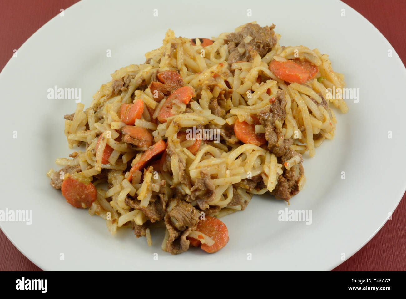 Sliced beef and carrots with rice noodles and sauce on white plate Stock Photo