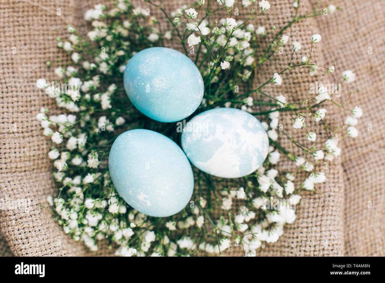 Stylish Easter eggs with spring flowers in floral nest on rustic fabric ...