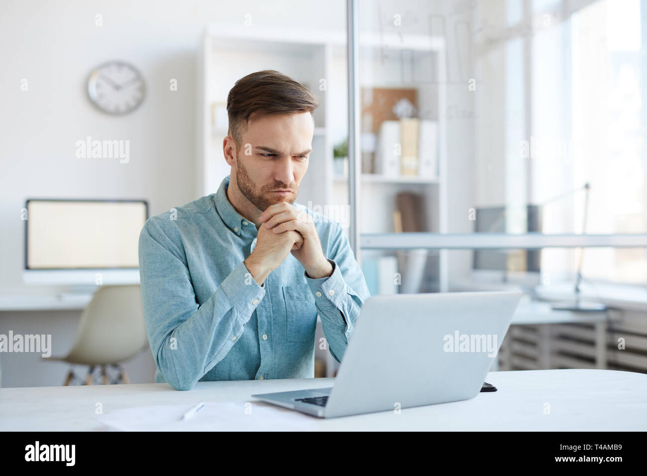 Pensive Young Man Using Laptop Stock Photo