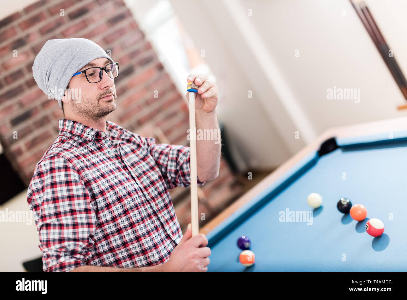 Portrait of modern young man chalking the snooker cue with chalk Stock