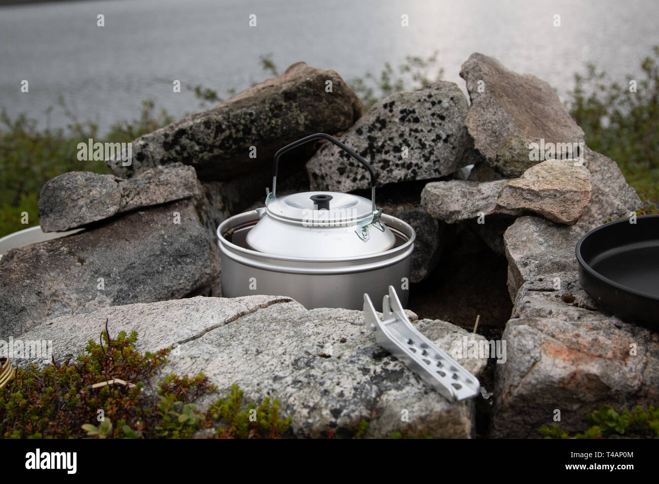 Camping stove and kettle nestled between rocks for shelter. Stock Photo