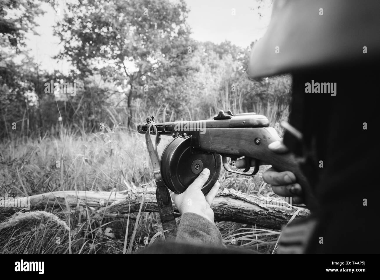 Hidden Re-enactor Dressed As German Wehrmacht Infantry Soldier In World War II Aiming a Russian Soviet Sub-Machine Gun PPSh-41 From Trench. WWII WW2 S Stock Photo