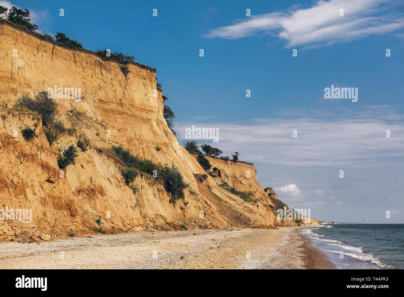 Beautiful view of sandy cliff near sea beach. Landscape of beach cliff and waves in sunny weather. Summer vacation concept. Exploring interesting plac Stock Photo