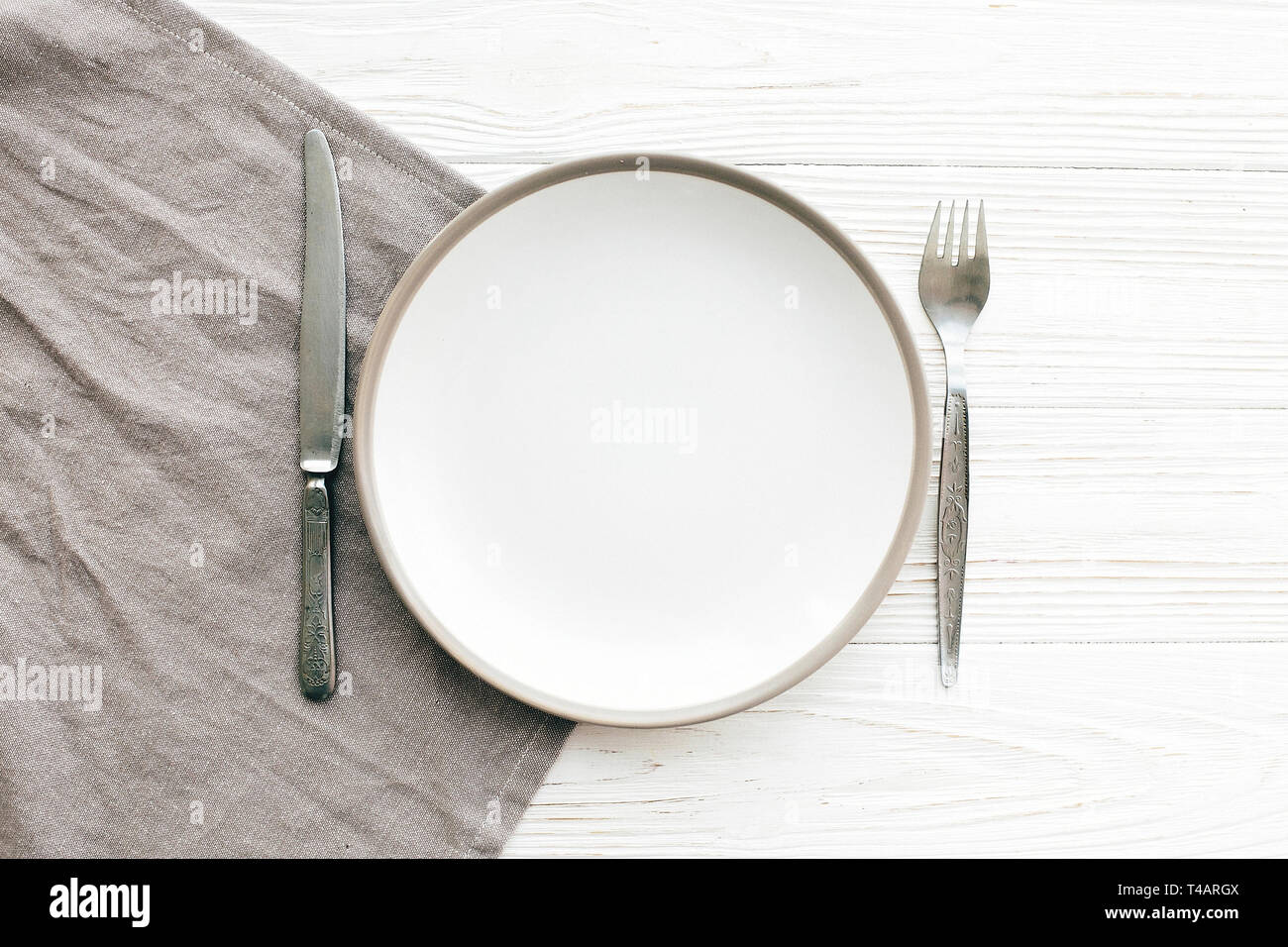 Stylish empty plate with vintage fork and knife on napkin on white ...