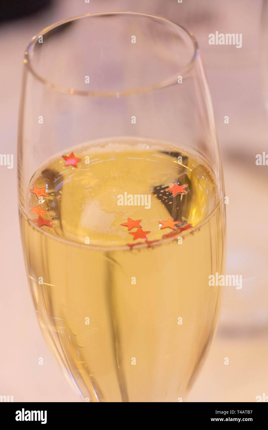 Champagne flute filled with champagne with star-shaped red glitter Stock Photo