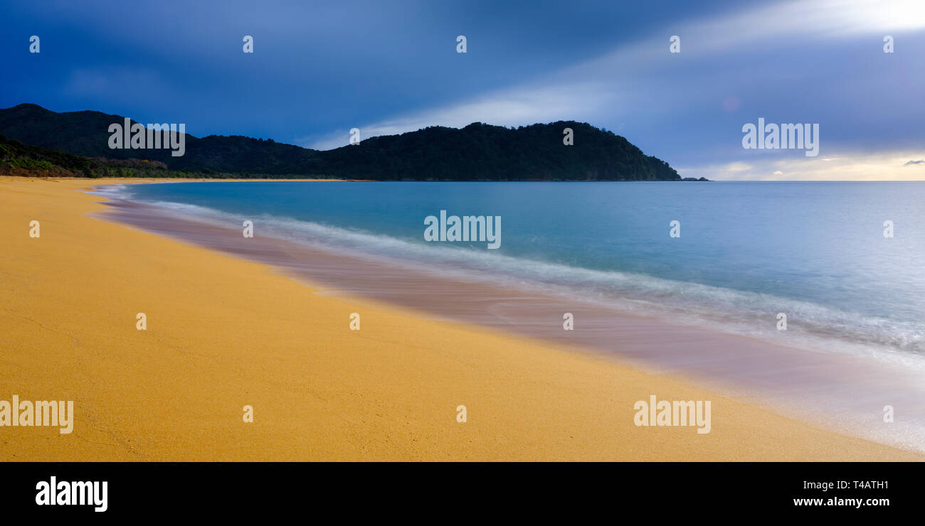 New Zealand, Nelson & Marlborough, Abel Tasman National Park. Dawn at the golden sand beach of Totaranui Bay which is bordered by native woodland and  Stock Photo