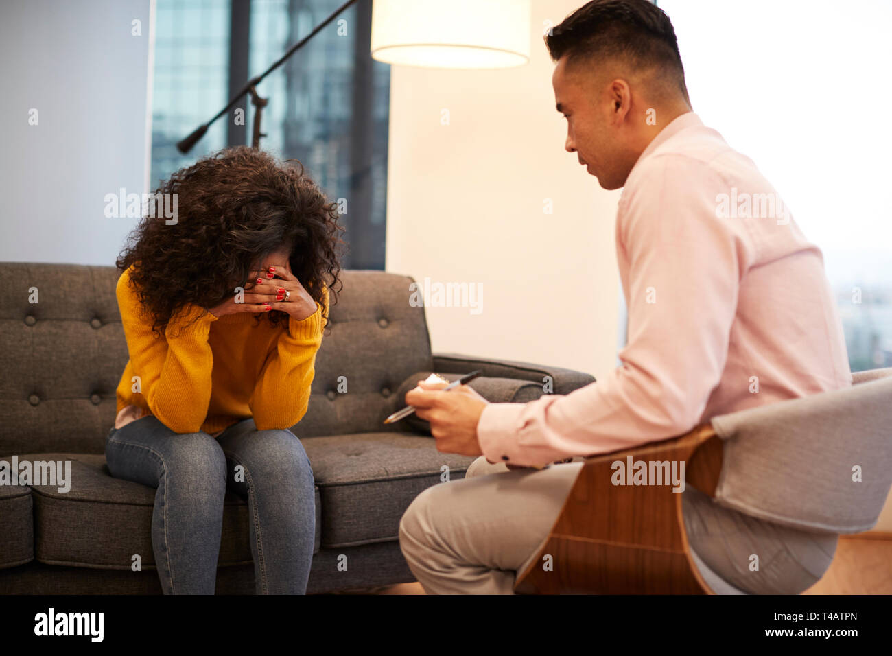 Unhappy Woman Sitting On Couch Meeting With Male Counsellor In Office Stock Photo