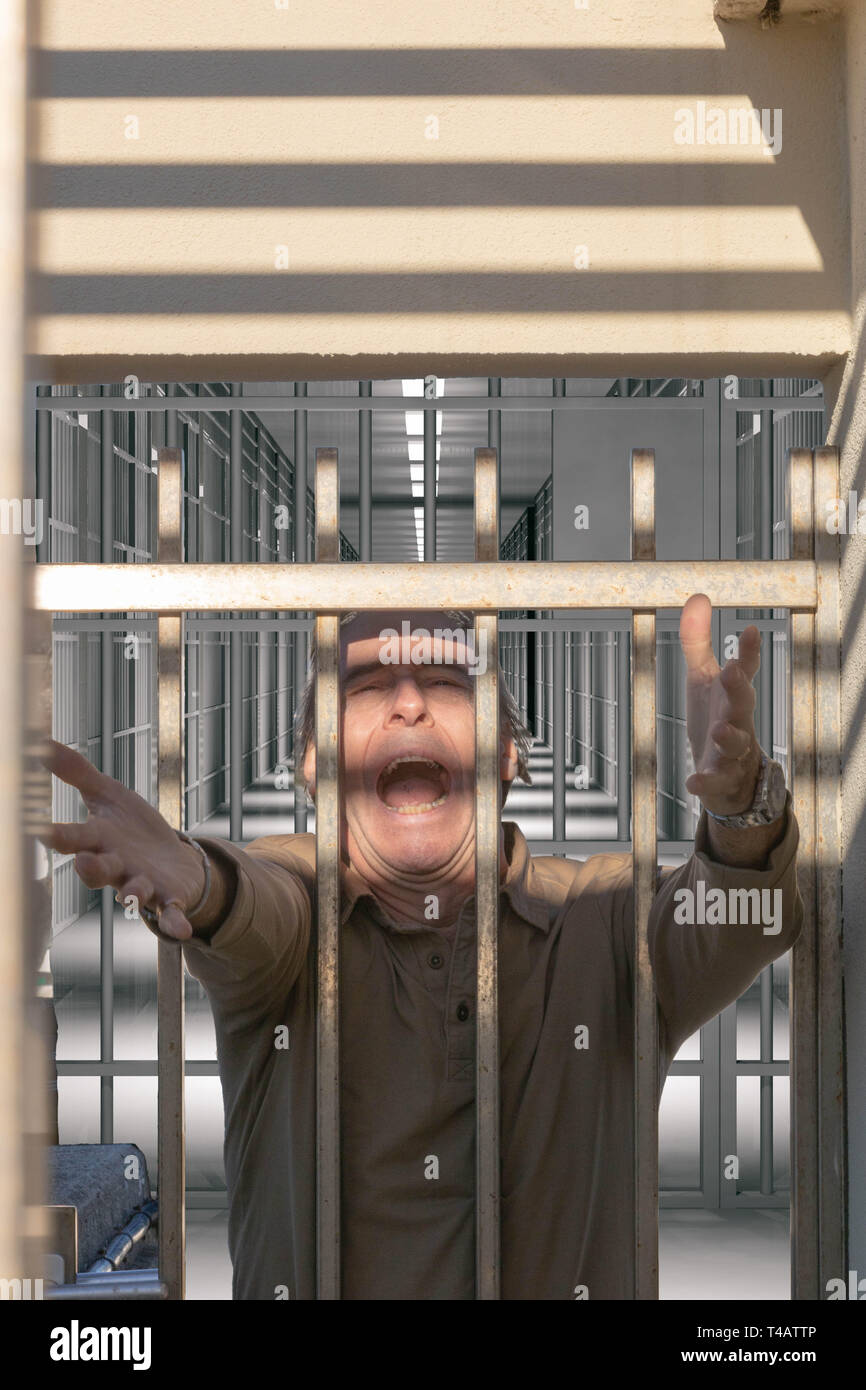 Man reaching out to freedom from a prison door screaming Stock Photo