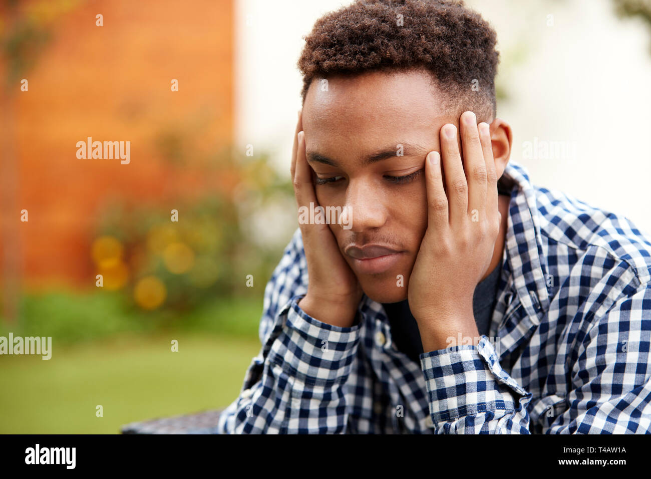 Depressed young black man with head in hands, close up, head and shoulders Stock Photo