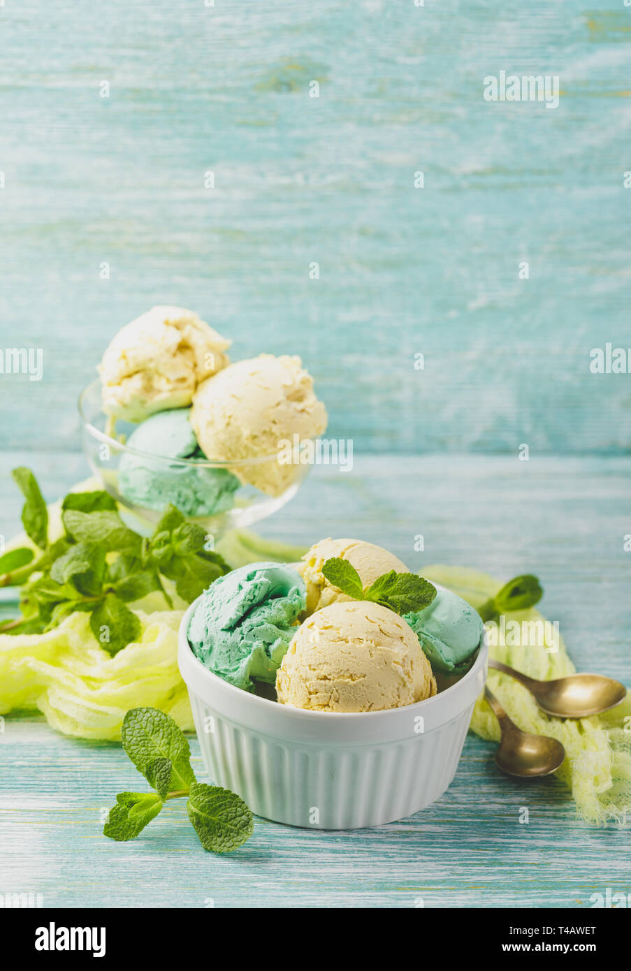 Mint and lemon ice cream with mint leaves in ceramic bowl on green wooden background Stock Photo