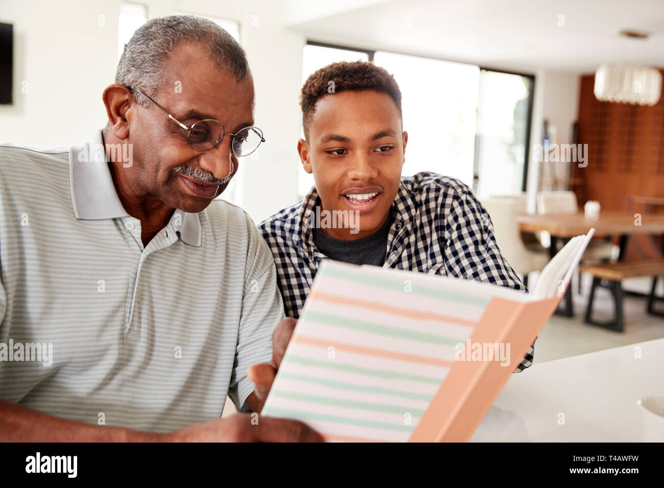 Young black man looking at a photo album at home with his grandfather, close up Stock Photo