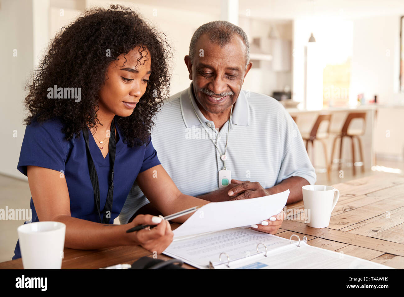 Female healthcare worker checking test results with a senior man during a home health visit Stock Photo