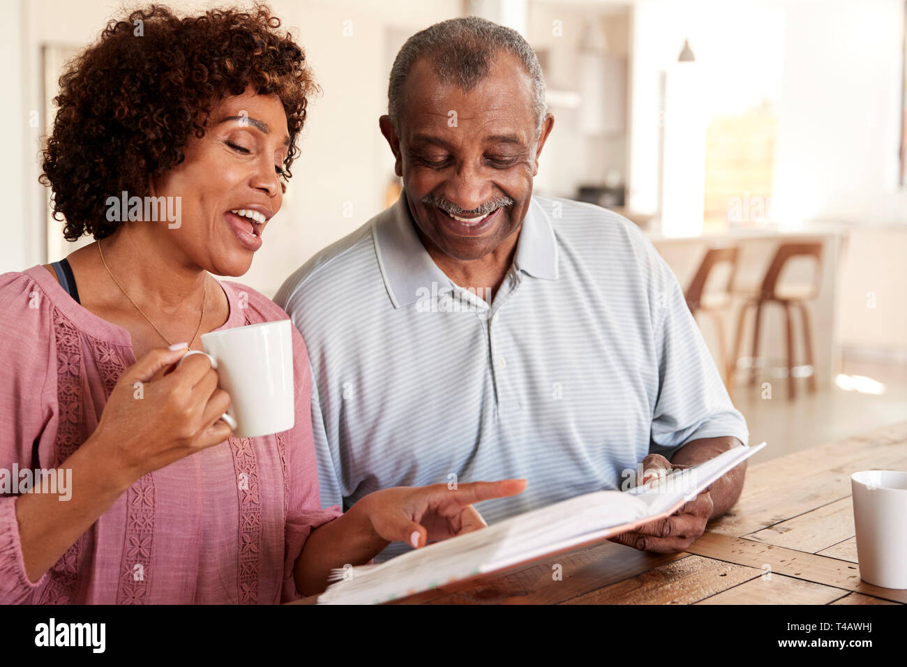 Senior black man and his middle aged daughter looking through photo album together at home, close up Stock Photo