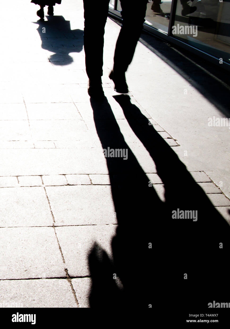 Blurry shadow silhouette of people walking in high contrast black and white Stock Photo
