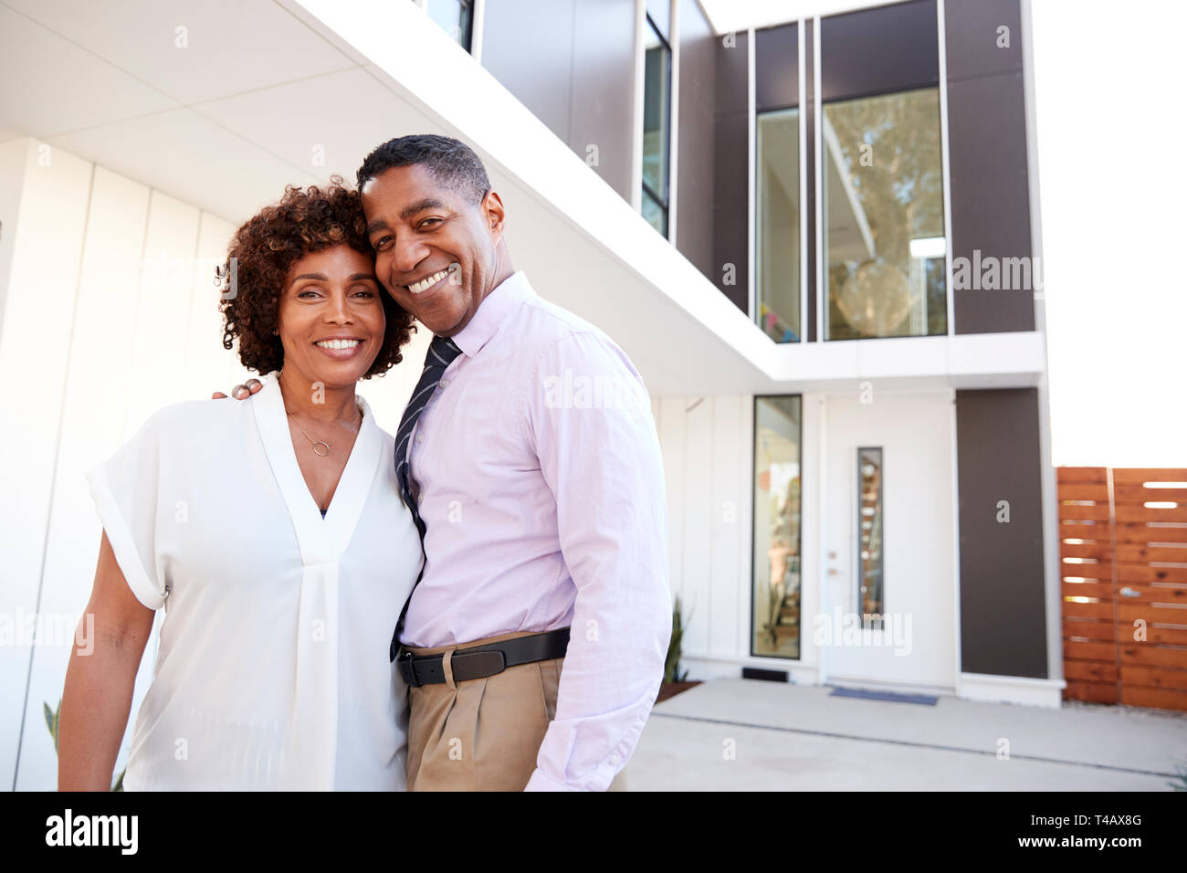 Middle aged black couple stand outside admiring their modern home, back view Stock Photo