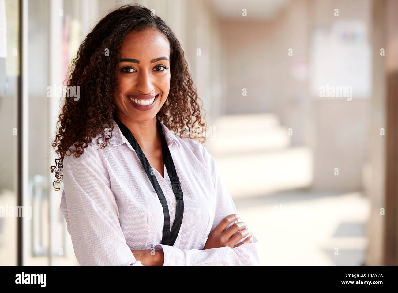 Portrait Of Smiling Female School Teacher Standing In Corridor Of ...