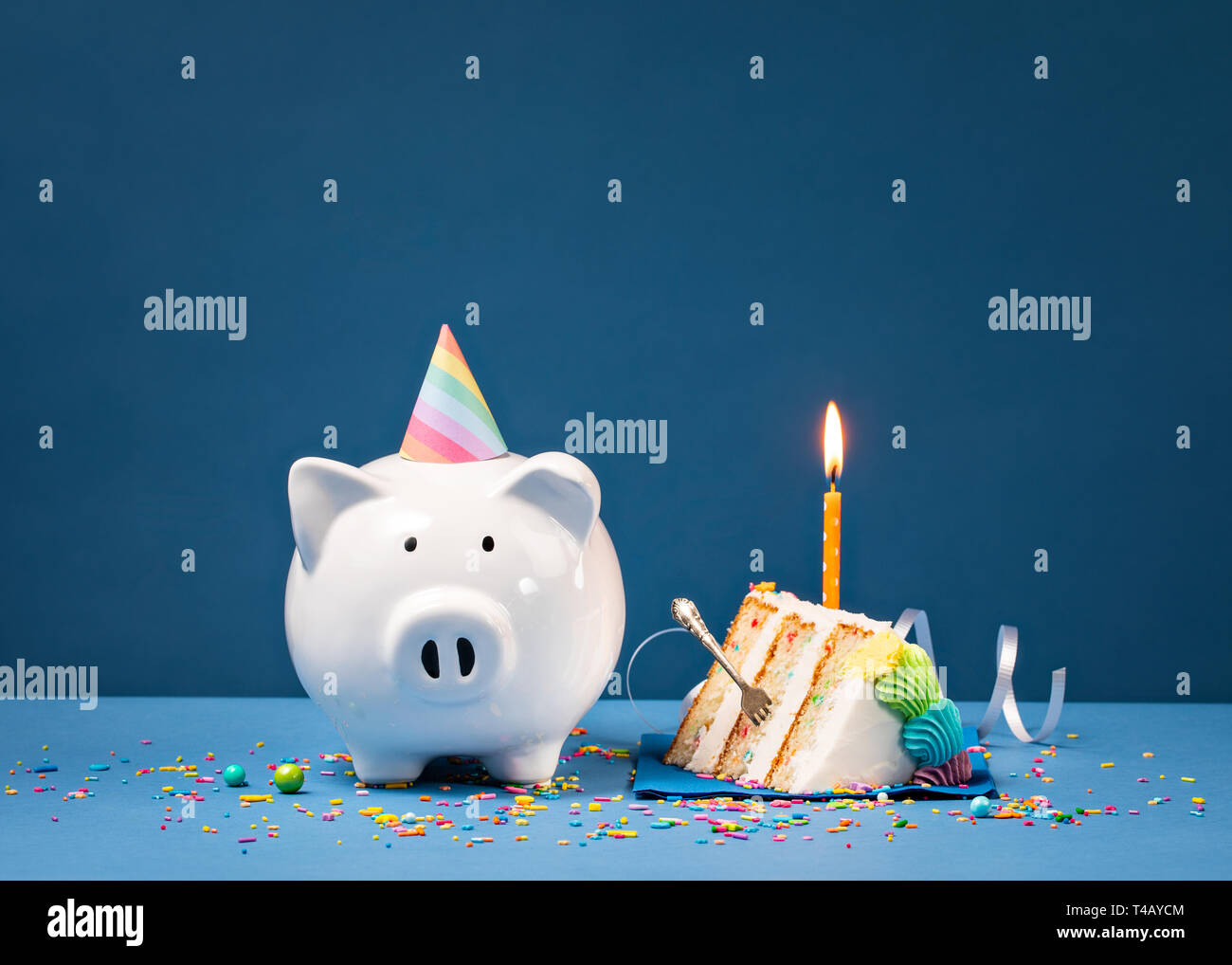 Slice of Cake with one Candle and Piggy Bank over a blue background
