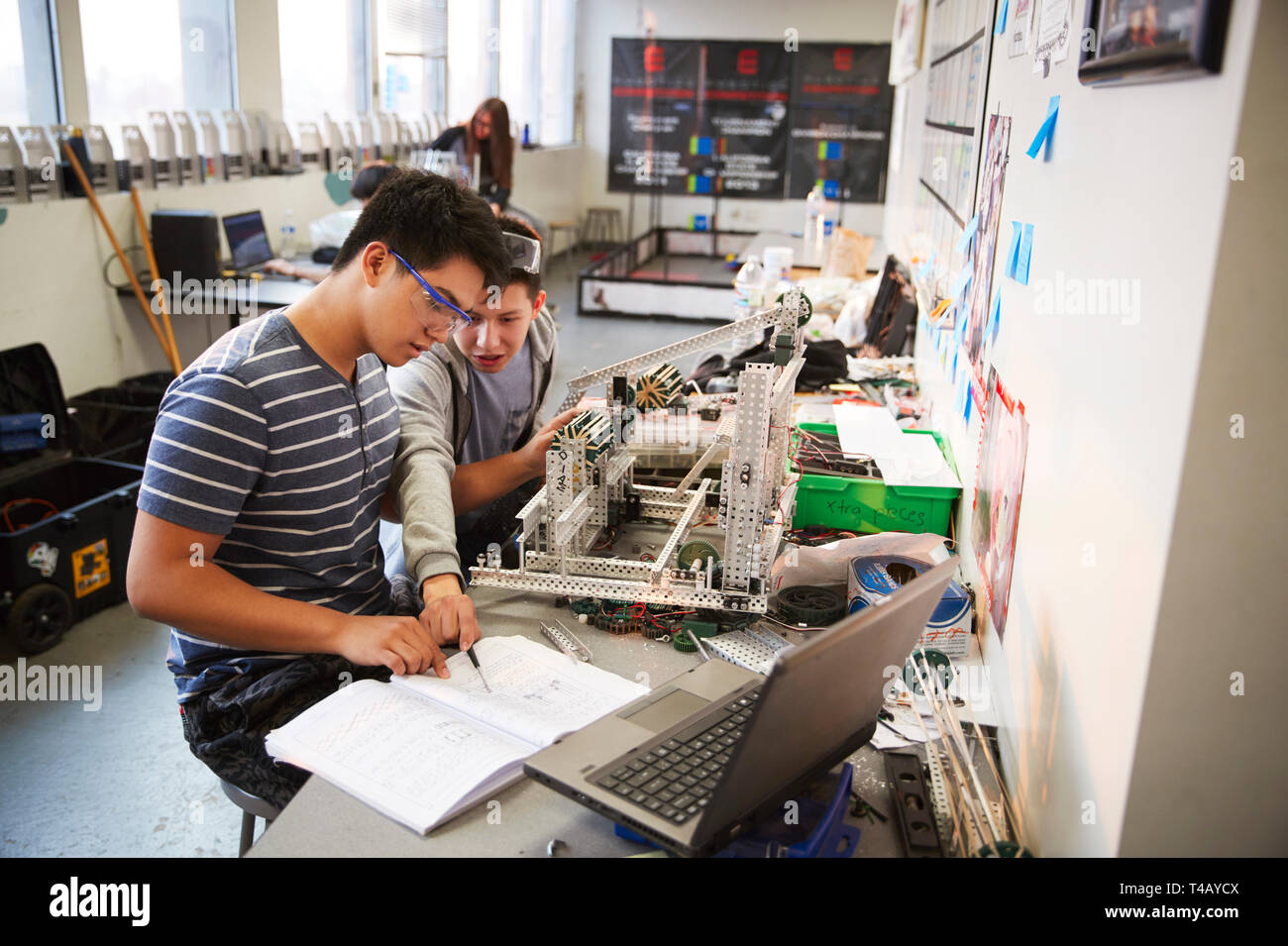Two Male College Students With Laptop Building Machine In Science