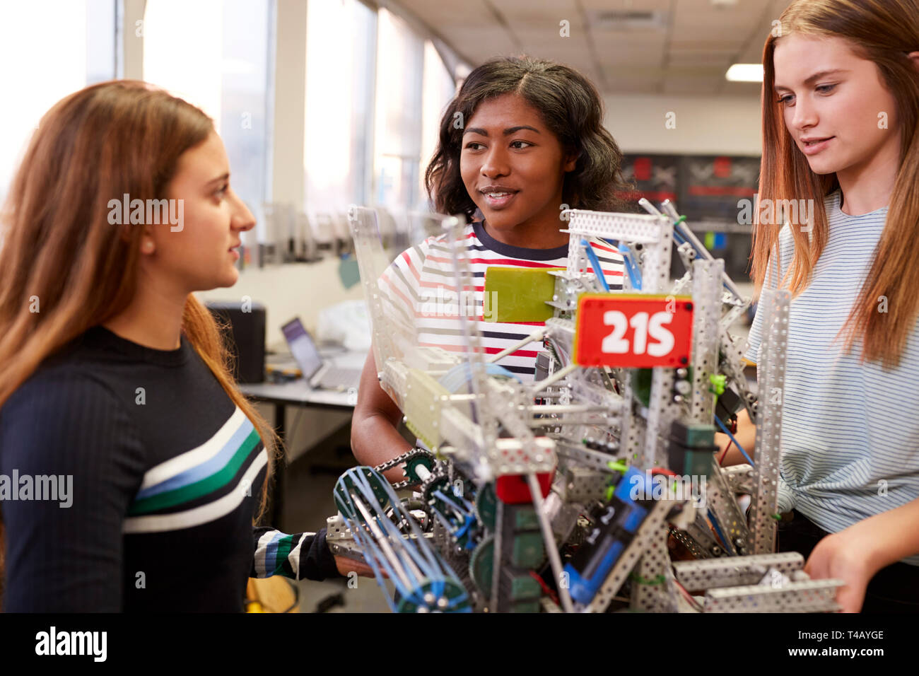 Female University Students Carrying Machine In Science Robotics Or Engineering Class Stock Photo
