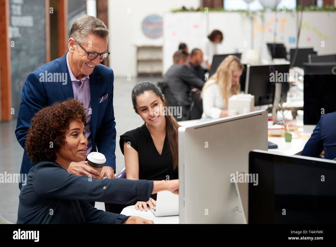 Businessman And Businesswomen Working At Computer On Desk In Open Plan Office Stock Photo
