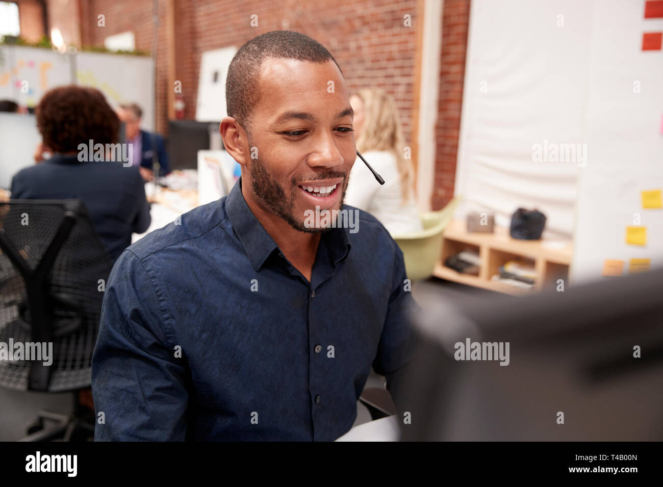 Male Customer Services Agent Working At Desk In Call Center Stock Photo