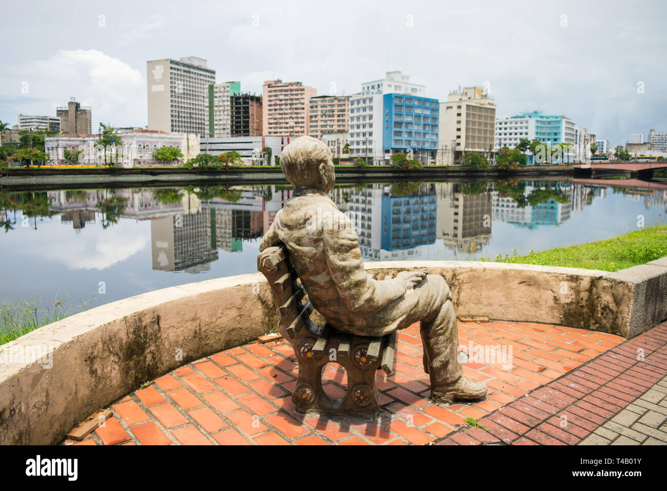 Statue of poet Joao Cabral de Melo Neto by the river Capibaribe - historic center in the background Stock Photo