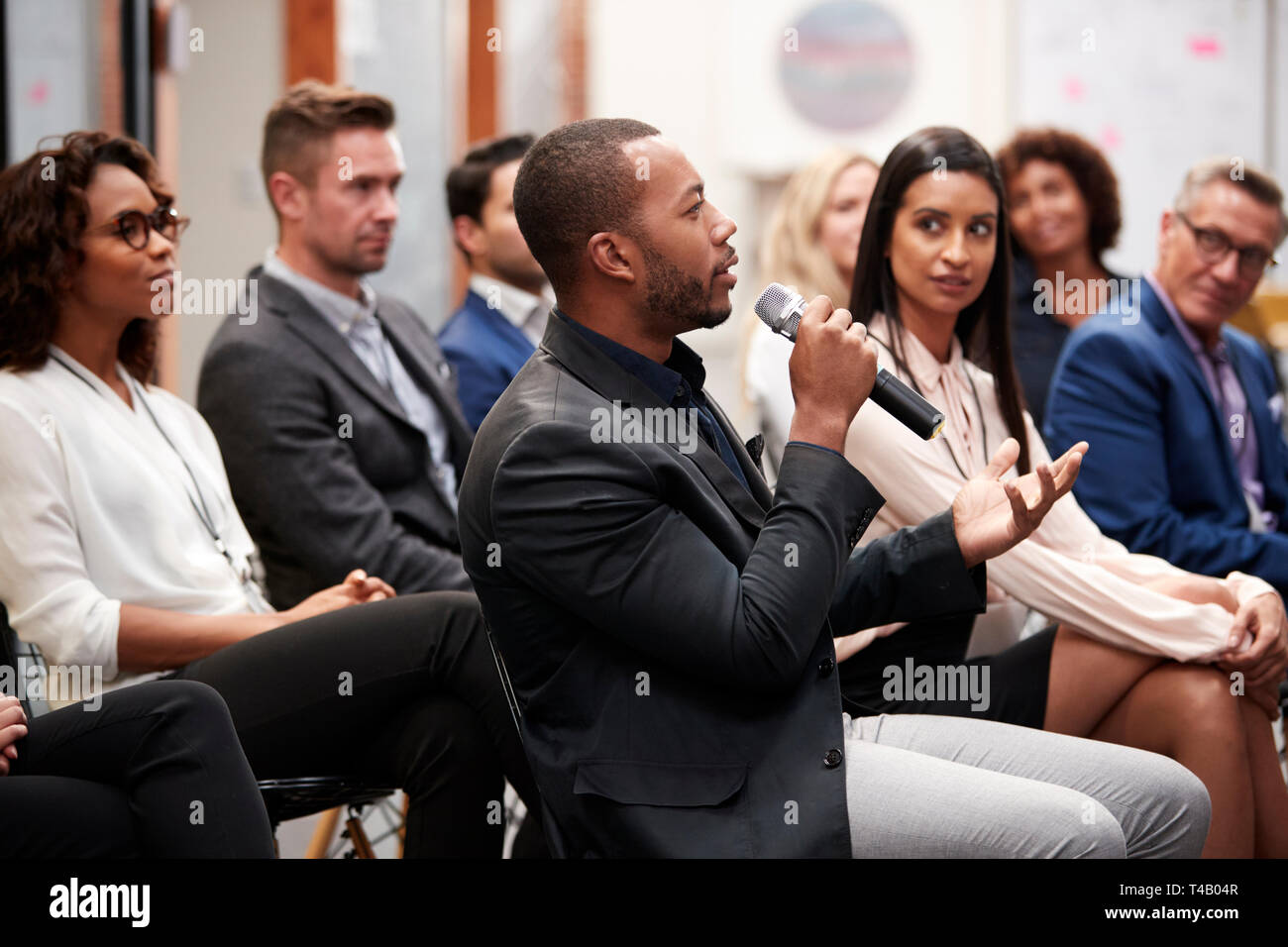 Group Of Businessmen And Businesswomen Applauding Presentation At Conference Stock Photo