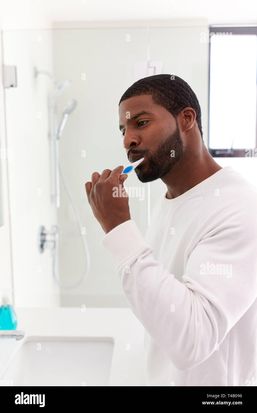 Man Looking At Reflection In Bathroom Mirror Brushing Teeth Stock Photo