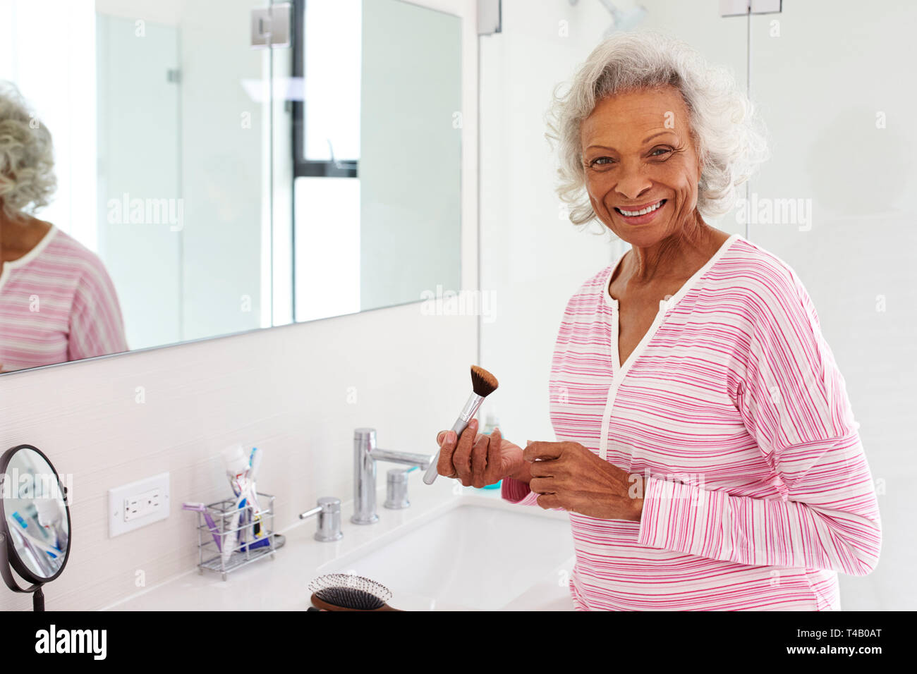 Portrait Of Senior Woman In Bathroom Putting On Make Up Stock Photo