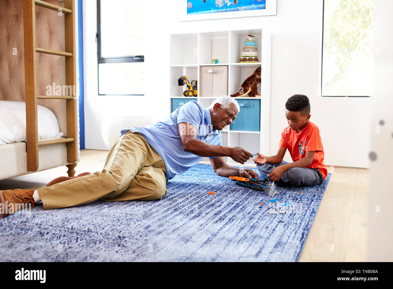 Grandfather With Grandson Lying On Rug At Home Building Robotic Model Together Stock Photo